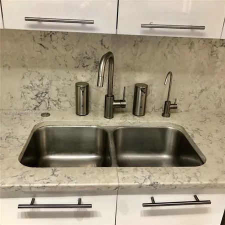 a kitchen sink with a stove and cabinets