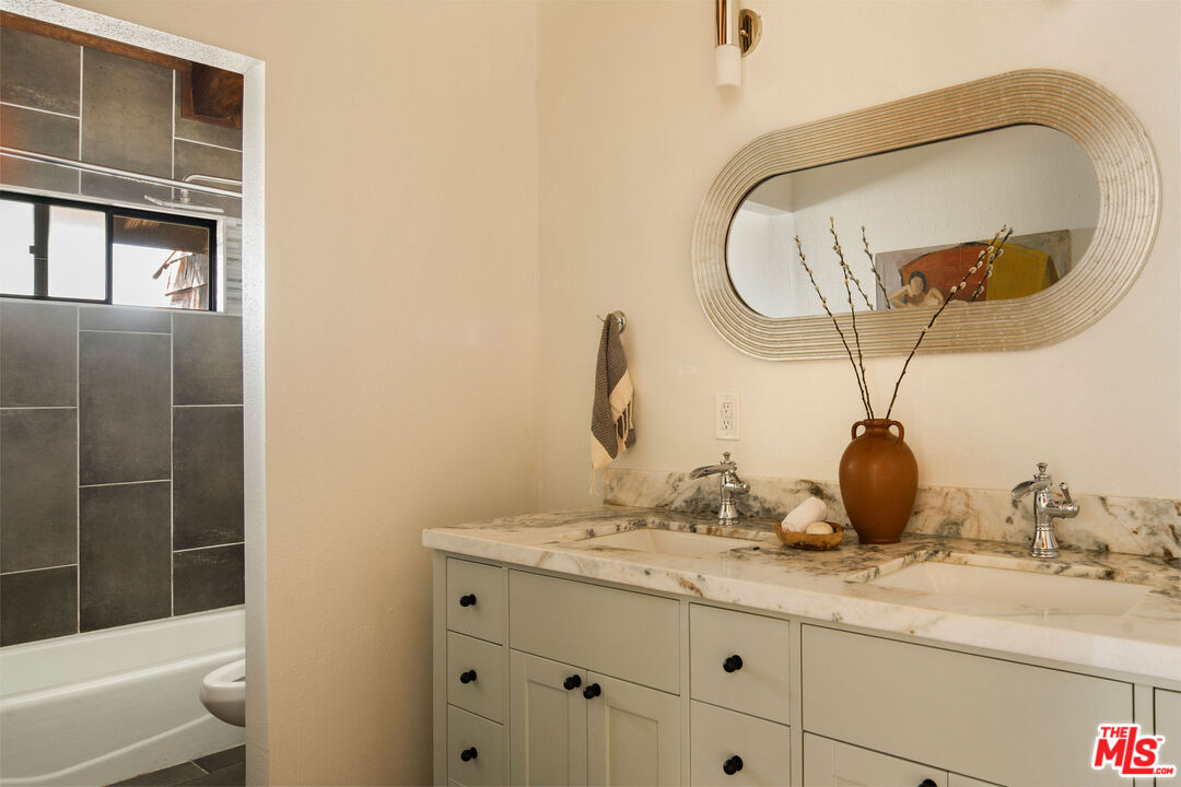 2996 Hyperion Avenue Los Angeles, CA 90027 - Photo 29 of 40 a bathroom with a granite countertop sink a mirror and shower