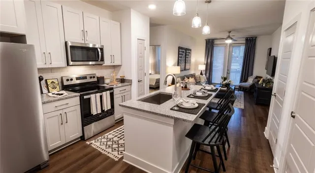 a kitchen with stainless steel appliances a stove a sink dishwasher a microwave oven a refrigerator with white cabinets and wooden floor