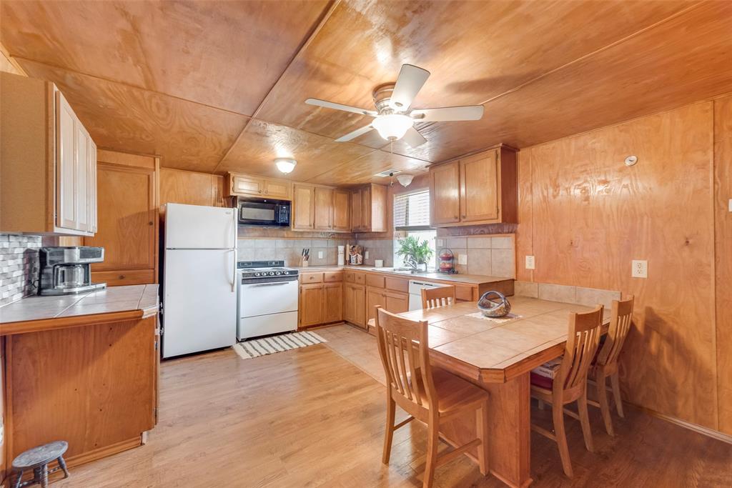 8636 Highway 31 Athens, TX 75751 - Photo 13 of 22 a kitchen with a dining table chairs refrigerator and cabinets