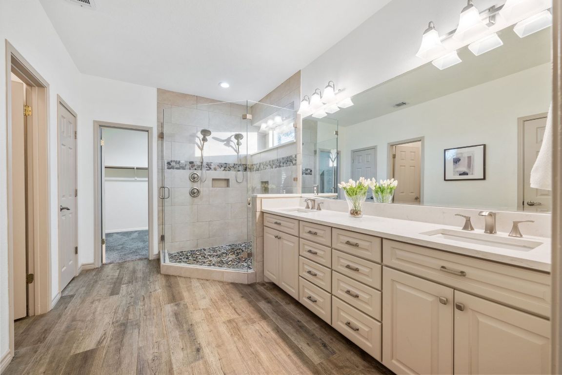 5100 Hadle Cove Austin, TX 78730 - Photo 13 of 32 First floor primary bathroom has been remodeled and feels like a spa with a beautiful shower with two shower heads, a long vanity with two sinks. Large walking closet.