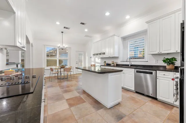 a kitchen with stainless steel appliances granite countertop a stove top oven a sink a dining table and chairs