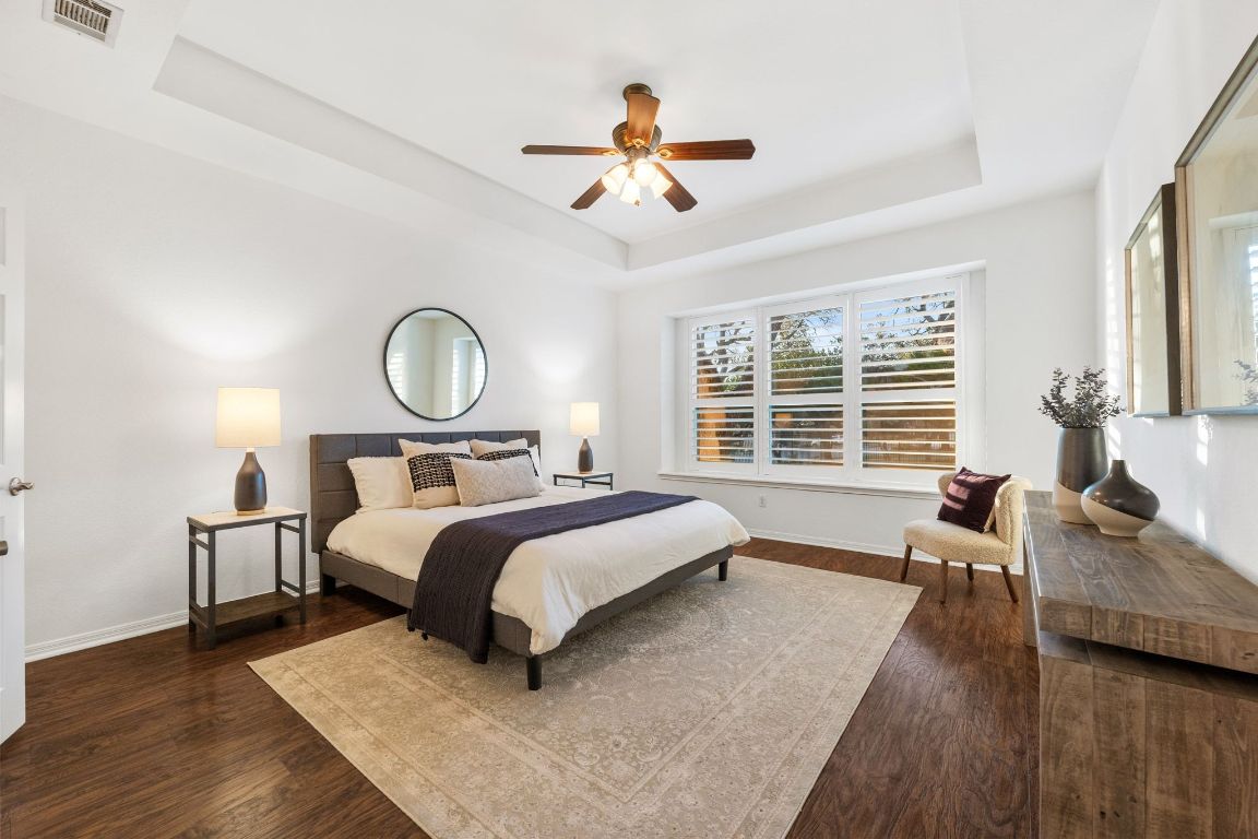 5100 Hadle Cove Austin, TX 78730 - Photo 5 of 32 The spacious primary bedroom is situated on the main level with beautiful wood floors, new windows that overlook the backyard and allow for natural light.