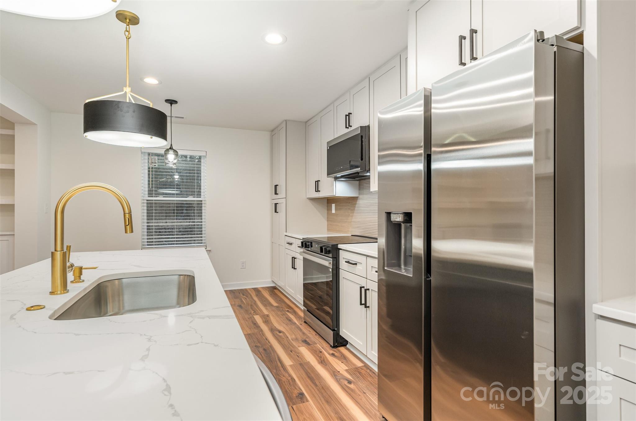 4169 Stack Road Harrisburg, NC 28075 - Photo 9 of 29 a kitchen with stainless steel appliances granite countertop a refrigerator a stove and a sink with wooden floor