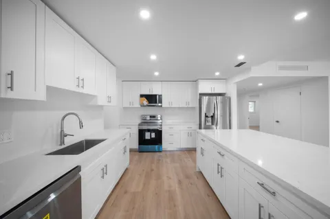 a large white kitchen with stainless steel appliances refrigerator a stove top oven with a oven and a refrigerator