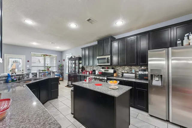a kitchen with kitchen island granite countertop stainless steel appliances and a sink