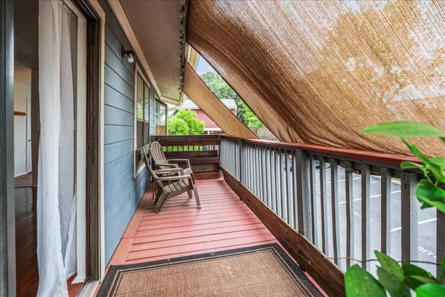 a balcony with wooden floor outdoor seating and yard in the back