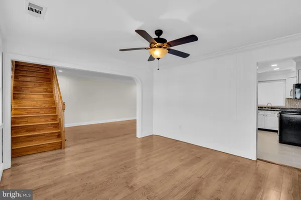 a view of a room with wooden floor and a ceiling fan