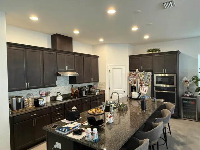 a kitchen with sink refrigerator stove dining table and chairs