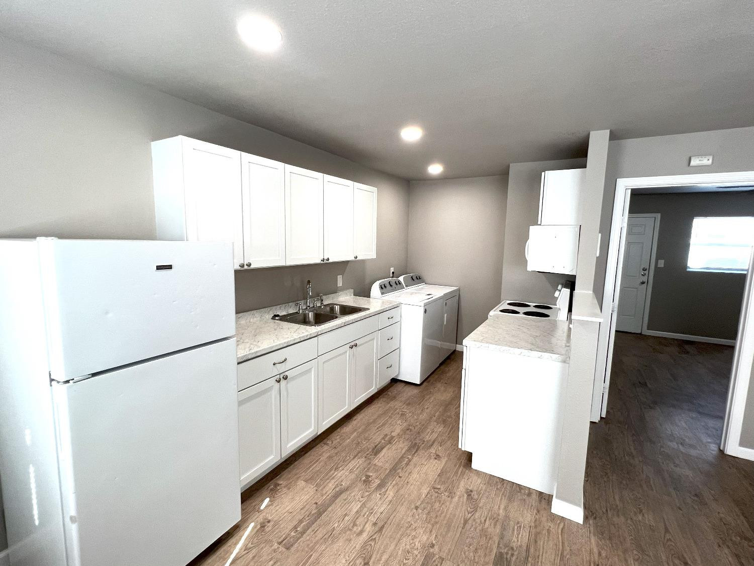 1201 36th Street, Unit C Lubbock, TX 79412 - Photo 4 of 7 a kitchen with a sink a refrigerator and white cabinets