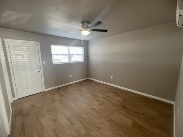 an empty room with wooden floor and windows