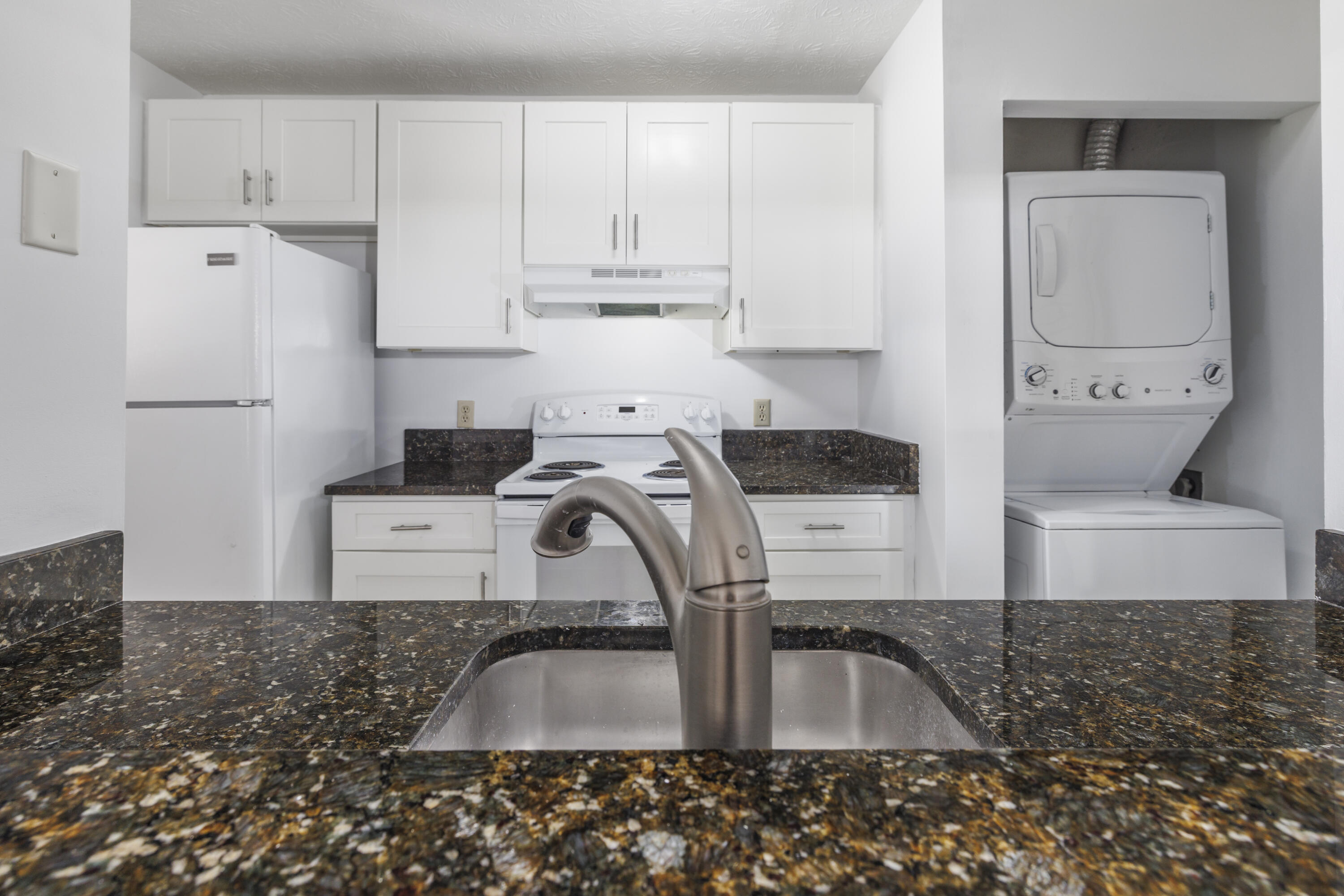 6541 Southeast Federal Highway, Unit 101 Stuart, FL 34997 - Photo 11 of 30 a kitchen with kitchen island granite countertop a sink a stove a refrigerator and white cabinets
