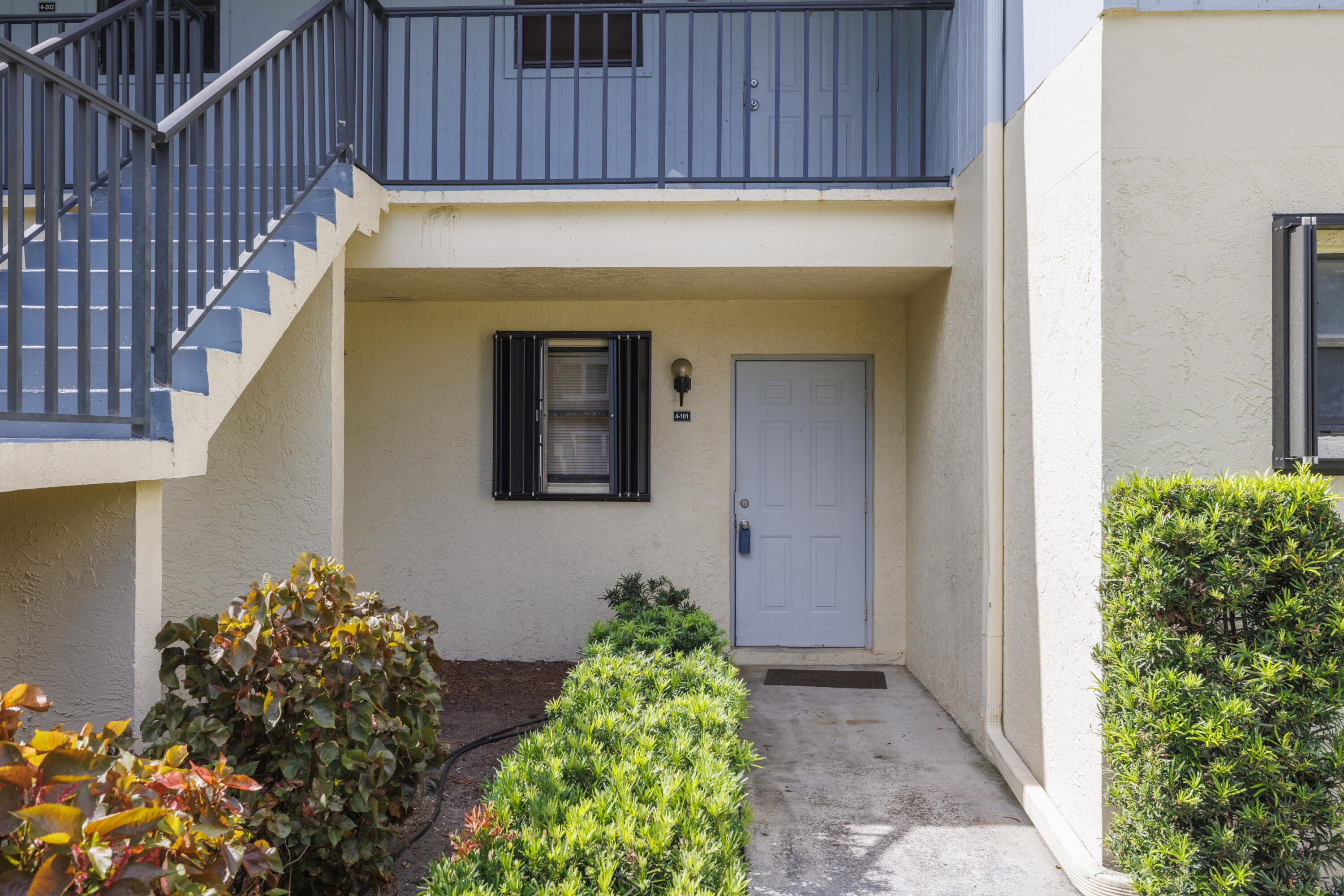 6541 Southeast Federal Highway, Unit 101 Stuart, FL 34997 - Photo 4 of 30 a view of a pathway of a house with potted plants and wooden wall