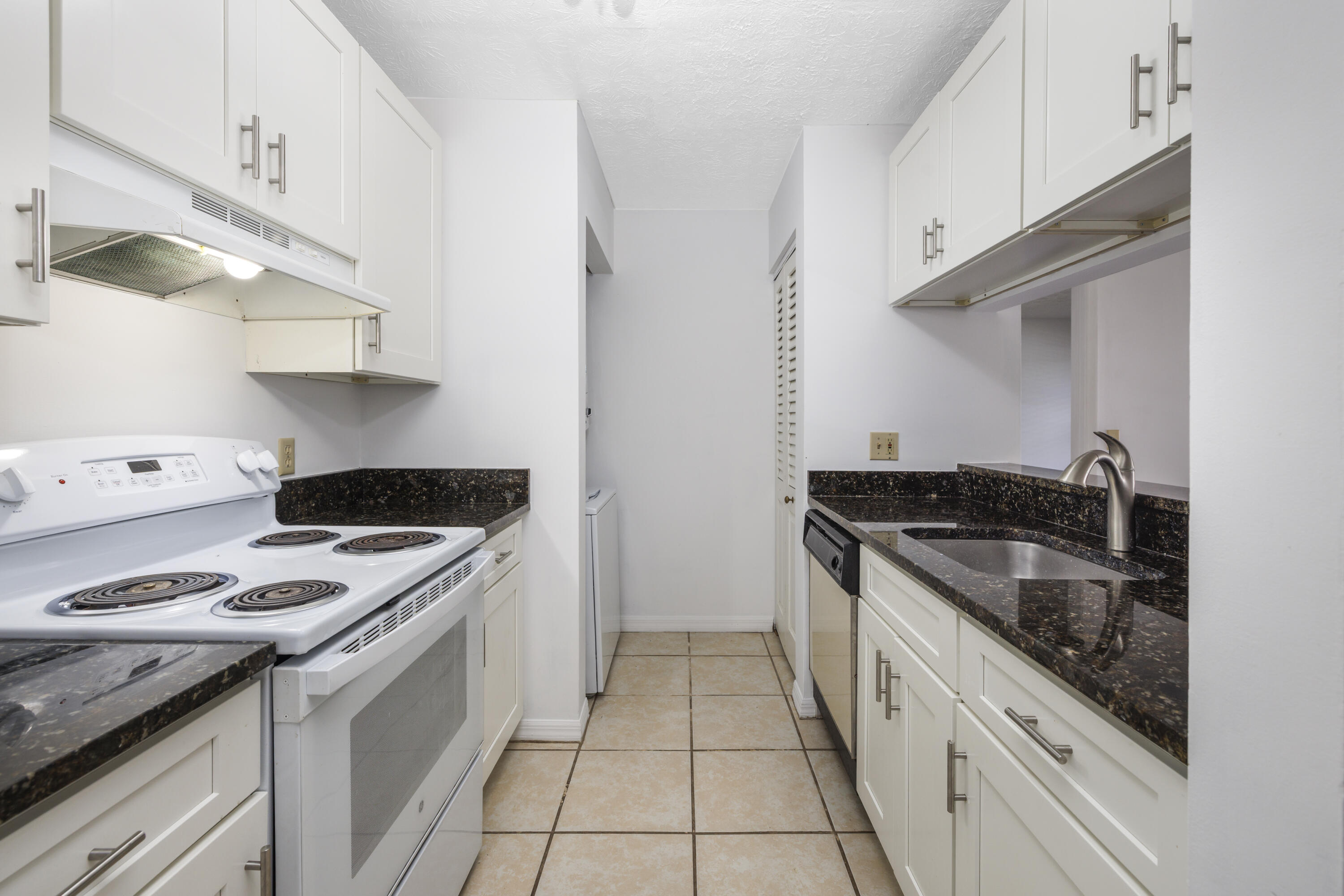 6541 Southeast Federal Highway, Unit 101 Stuart, FL 34997 - Photo 10 of 30 a kitchen with granite countertop stainless steel appliances a sink stove and cabinets