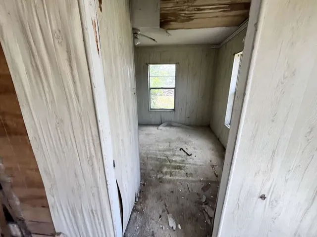 a view of a hallway to a livingroom with wooden floor and a window