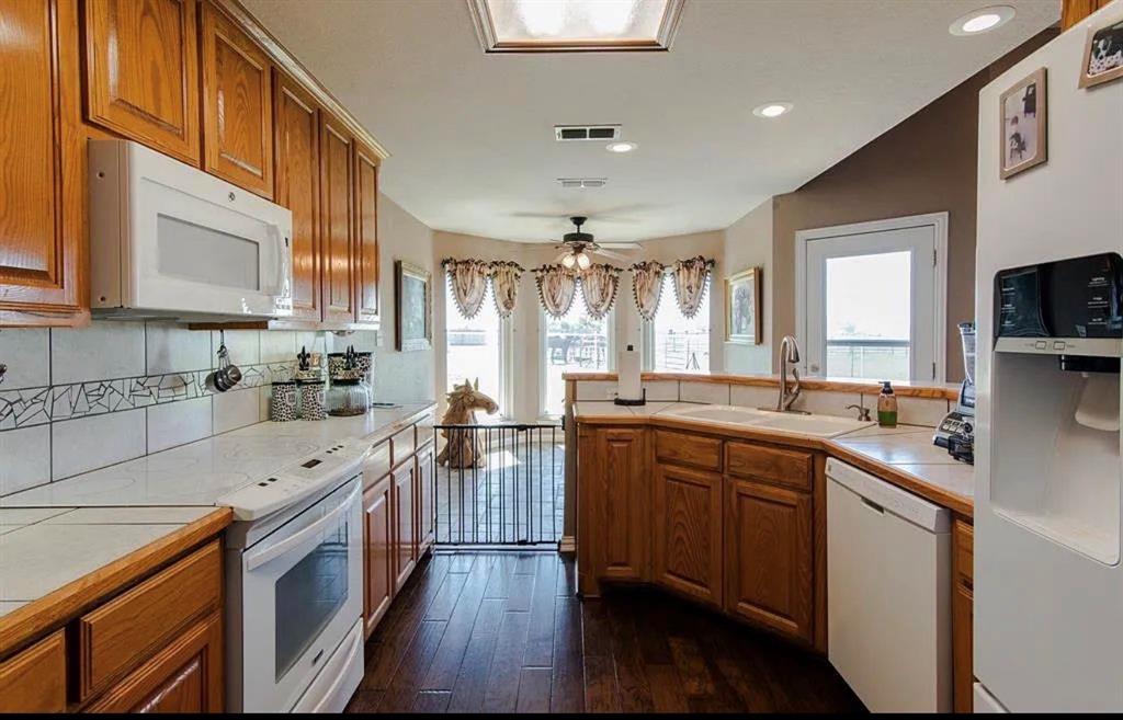 10899 Jackson Road Krum, TX 76249 - Photo 3 of 11 Kitchen with white appliances, tile countertops, wood finish cabinets, dark wood-style flooring, and a ceiling fan