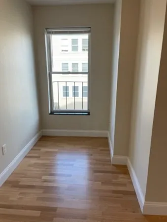 an empty room with wooden floor and windows