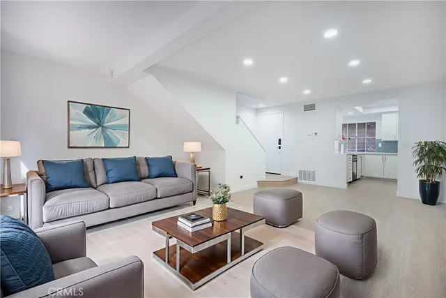 a living room with furniture potted plant and kitchen view