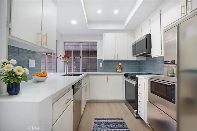 a kitchen with stainless steel appliances a stove a sink a microwave a stove and white cabinets