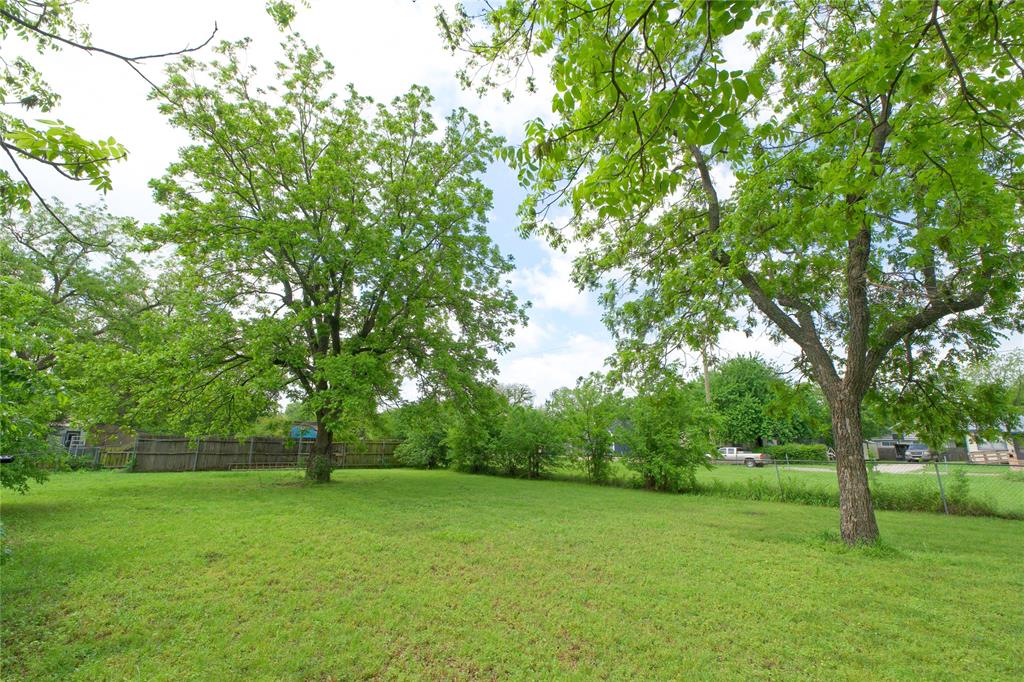 714 Potter Street Gainesville, TX 76240 - Photo 7 of 12 The property features an expansive green lawn with mature trees and a partial wooden fence
