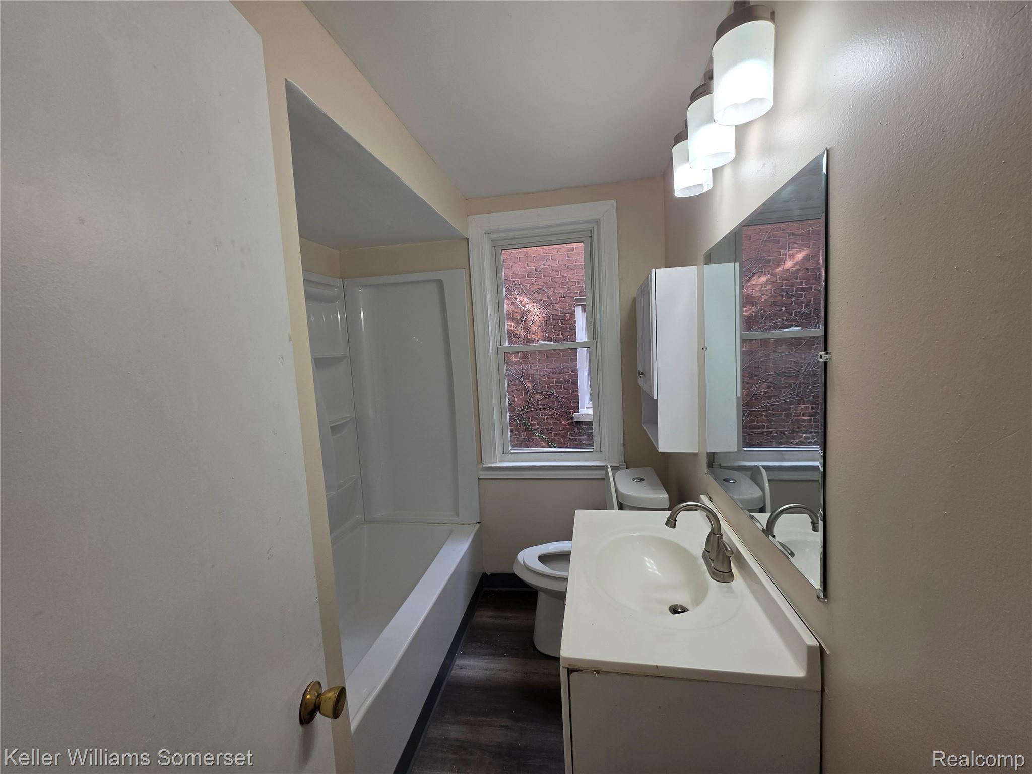 12609 Santa Rosa Drive Detroit, MI 48238 - Photo 7 of 11 Bathroom featuring a combination tub/shower, single vanity with integrated sink, wood-finish flooring, and a wall-mounted medicine cabinet