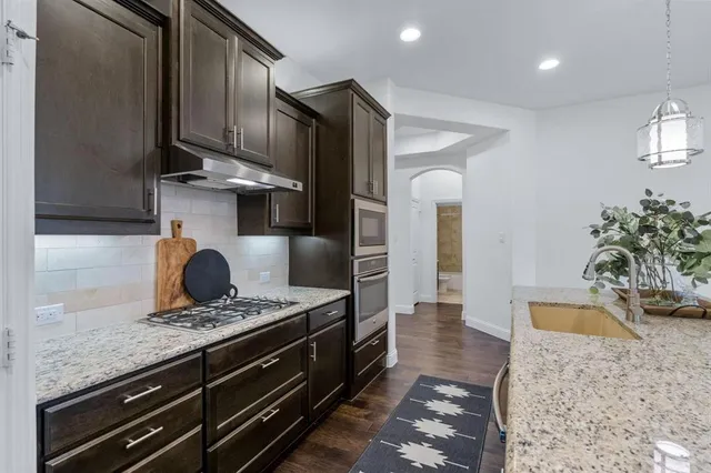 a kitchen with stainless steel appliances granite countertop a sink a stove and a refrigerator