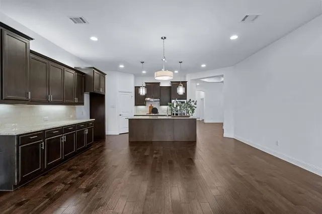 a kitchen with stainless steel appliances granite countertop a sink a stove and a wooden floors