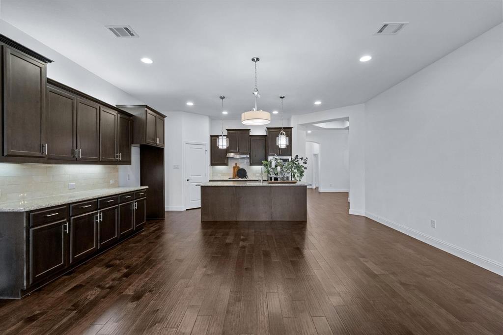 4220 Harper Avenue Celina, TX 75009 - Photo 9 of 20 a large kitchen with stainless steel appliances kitchen island a large counter top and wooden floors