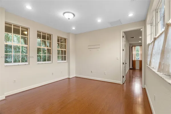 an empty room with wooden floor and windows