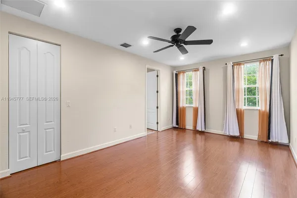 a view of an empty room with a window and wooden floor