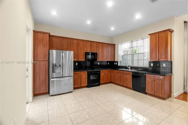 a large kitchen with granite countertop a refrigerator and a stove top oven