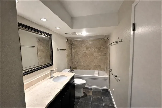 a bathroom with a granite countertop sink toilet and shower