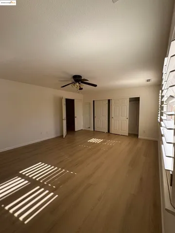 an empty room with windows and chandelier fan