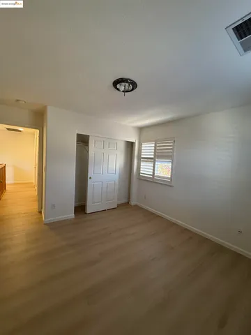 an empty room with window and closet area