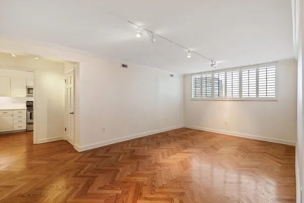 a view of an empty room with wooden floor and a ceiling fan