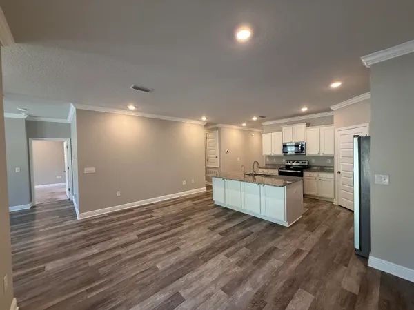 a kitchen with stainless steel appliances kitchen island granite countertop a stove a refrigerator and a sink with wooden floor