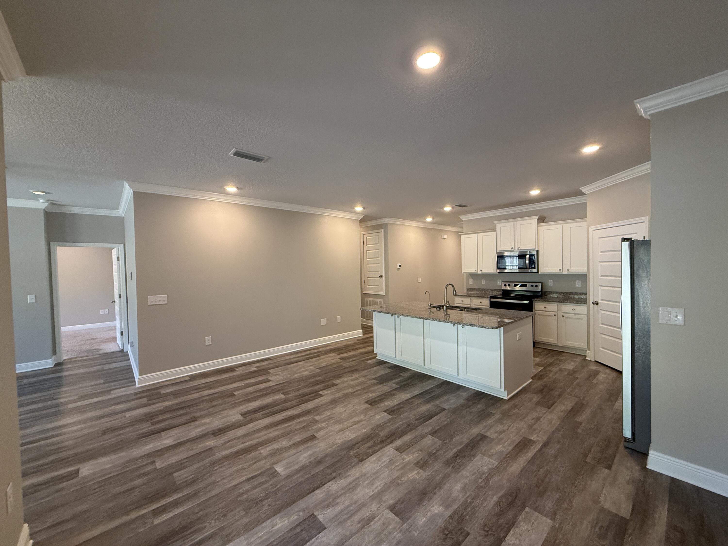 491 Lightning Bug Lane, Unit LOT 11 Freeport, FL 32439 - Photo 15 of 34 a kitchen with stainless steel appliances kitchen island granite countertop a stove a refrigerator and a sink with wooden floor