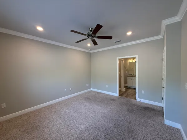 an empty room with a ceiling fan and carpet