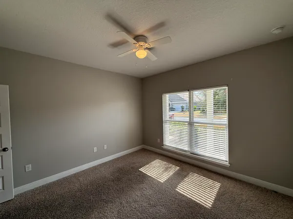 an empty room with windows and fan
