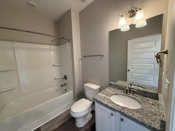 a bathroom with a granite countertop sink a toilet and shower