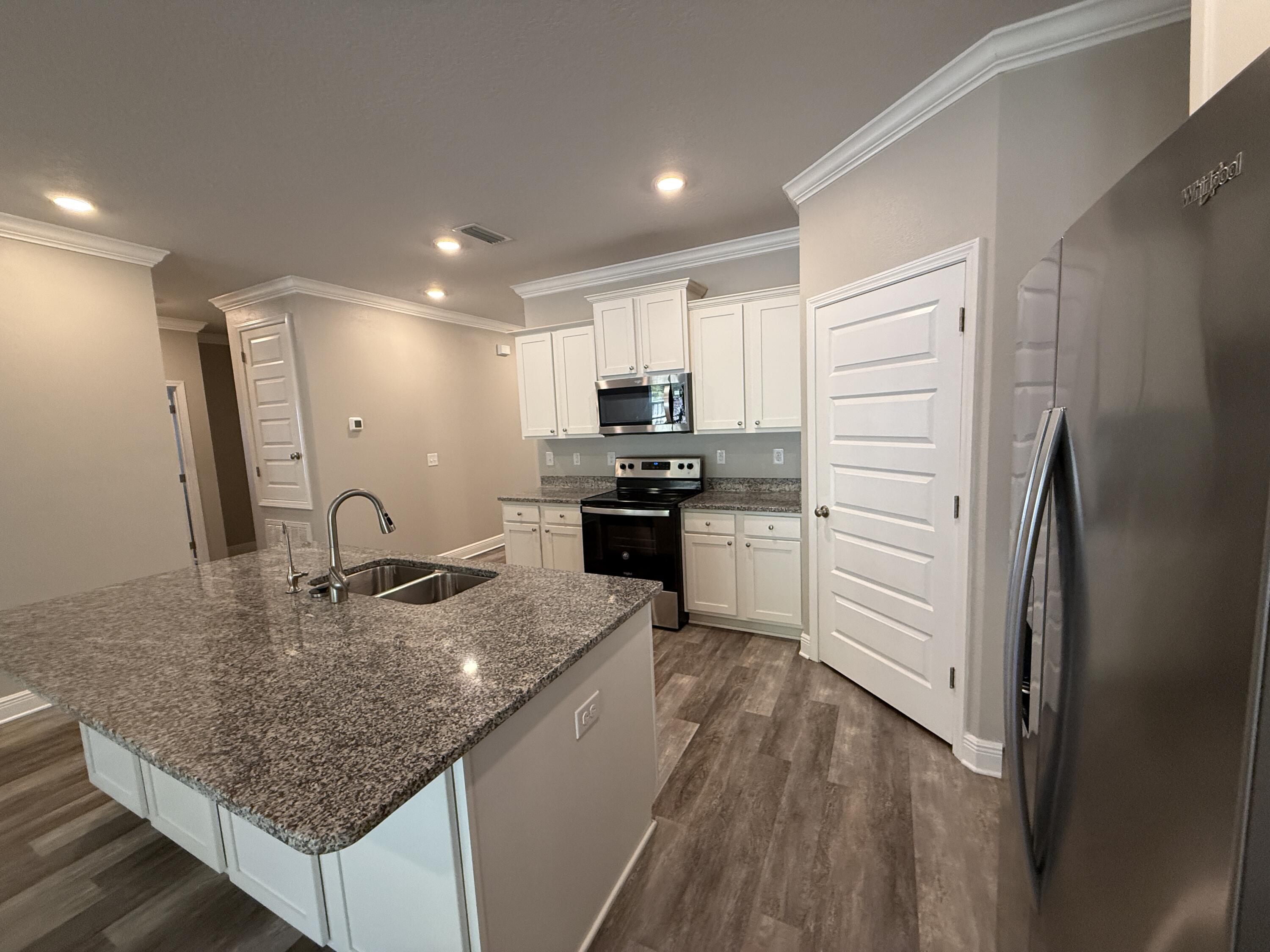 491 Lightning Bug Lane, Unit LOT 11 Freeport, FL 32439 - Photo 10 of 34 a kitchen with a refrigerator a sink and a stove top oven with wooden floor