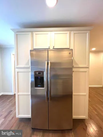 a kitchen with a refrigerator and wooden floor