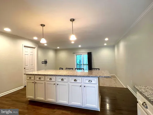 a view of a kitchen island a chandelier and wooden floor