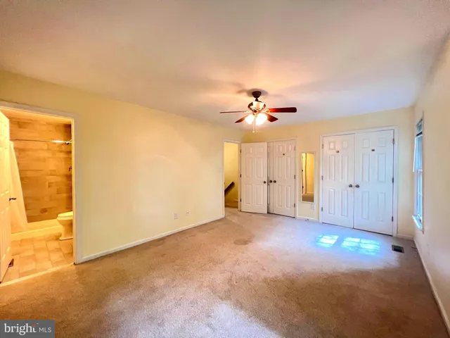 an empty room with windows and chandelier fan