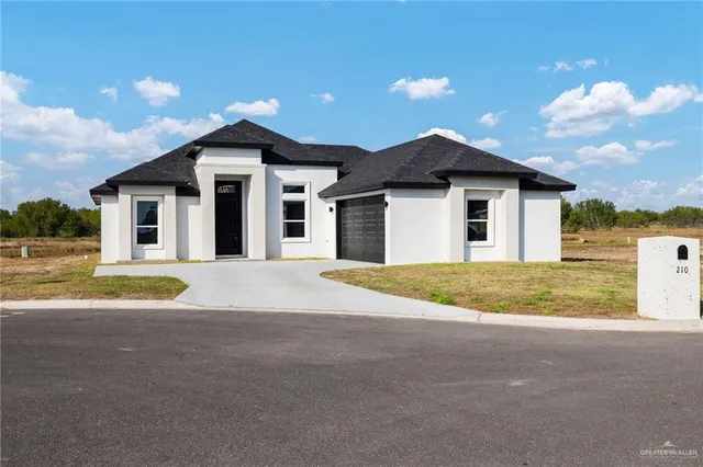 a view of yellow house with a yard and large trees