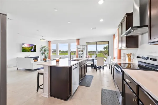 a view of a kitchen with kitchen island stainless steel appliances a stove a sink a dining table and chairs