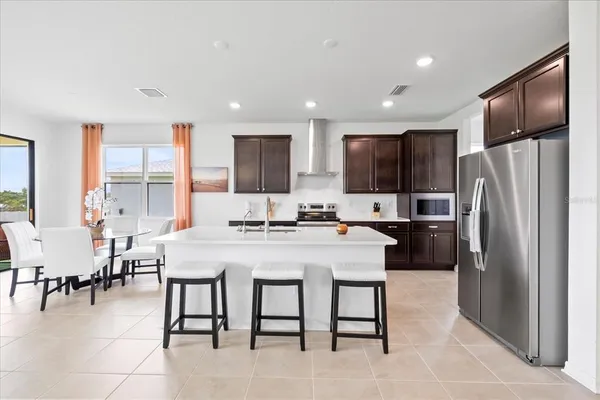 a kitchen with stainless steel appliances granite countertop a refrigerator a sink a stove a dining table and chairs