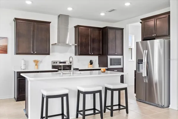 a kitchen with stainless steel appliances granite countertop a refrigerator a stove a sink and a microwave