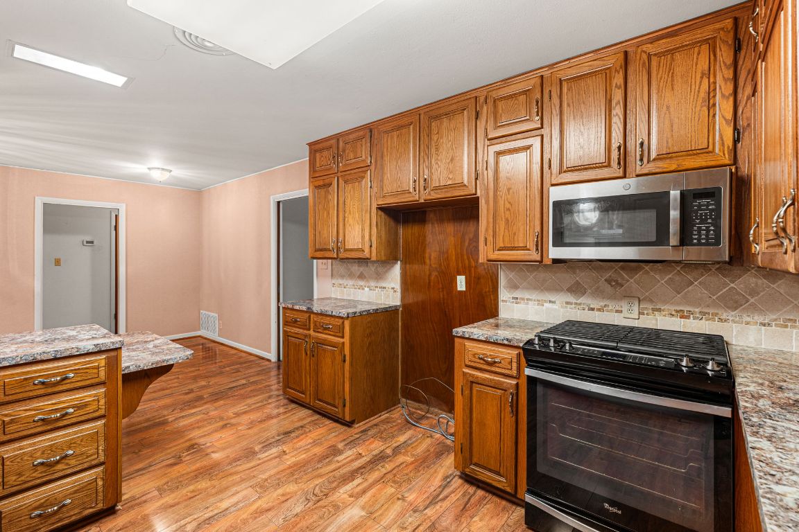 1800 Barbara Street Austin, TX 78757 - Photo 15 of 37 a kitchen with granite countertop wooden cabinets and stainless steel appliances