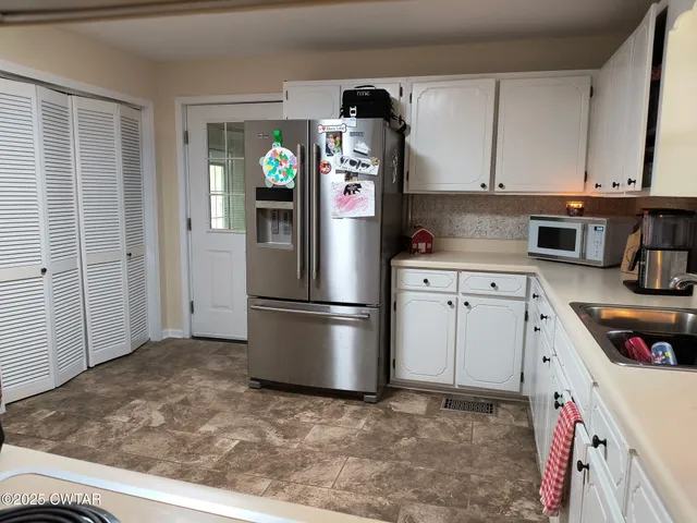 a kitchen with stainless steel appliances granite countertop a refrigerator a stove and a sink